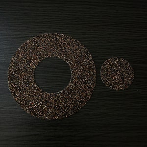 May include: Two round, black and gold glitter circles with a hole in the center of the larger circle.