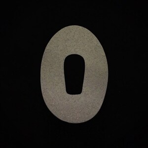 May include: A white, oval-shaped patch with a smaller, black, oval-shaped hole in the centre. The patch has a textured, glittery surface.
