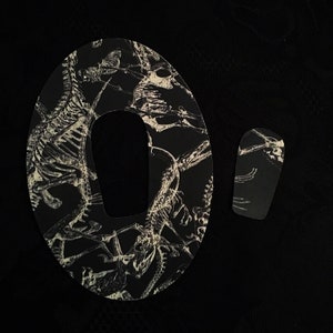 May include: A black and white patterned mousepad with a skeleton design. The mousepad has a cut-out for a mouse.