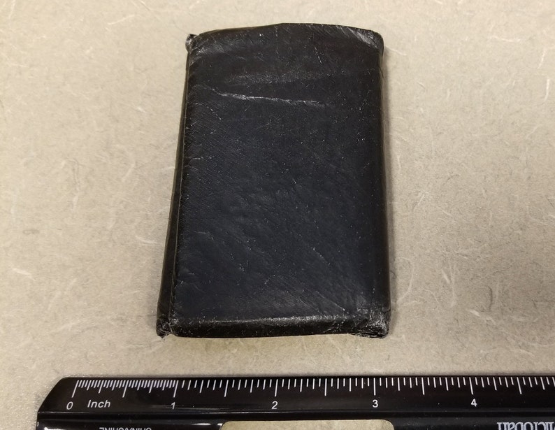 May include: A black leather wallet with a worn and distressed look. The wallet is closed and appears to be made of a high-quality material.
