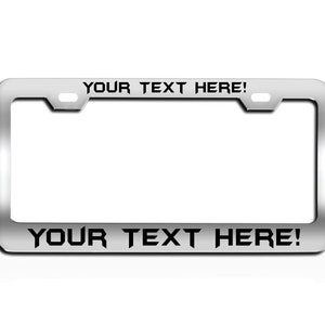 May include: A silver metal license plate frame with black text that reads "YOUR TEXT HERE!" on the top and bottom.