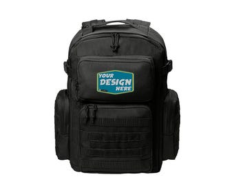Könnte beinhalten: Schwarzer taktischer Rucksack mit mehreren Taschen und einer großen Fronttasche mit dem Text "YOUR DESIGN HERE" in einem blauen und grünen Rechteck.