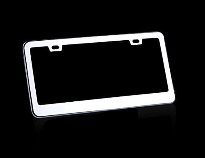 May include: A white metal license plate frame with rounded corners. The frame has two holes on the top and two holes on the bottom for mounting.