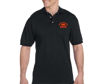 May include: A black short-sleeved polo shirt with a small orange embroidered design on the left chest that says "YOUR DESIGN HERE".