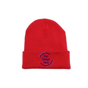 May include: Red knit beanie with a fold-over cuff. The beanie has a blue and white circle with the text "Your Design Here" on the front.