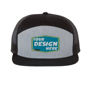 Könnte beinhalten: Schwarze und graue Trucker-Kappe mit Netzrücken. Das vordere Panel hat einen grauen Patch mit dem Text "YOUR DESIGN HERE" in einem blauen und gelben Rechteck.