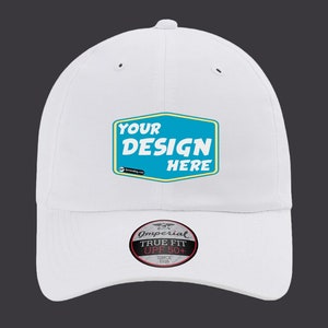 May include: White baseball cap with a blue and yellow patch that says "YOUR DESIGN HERE". The cap also has a black and white label that says "Imperial True Fit UPF 50+" on the front.