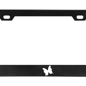 May include: Black metal license plate frame with a white butterfly design.