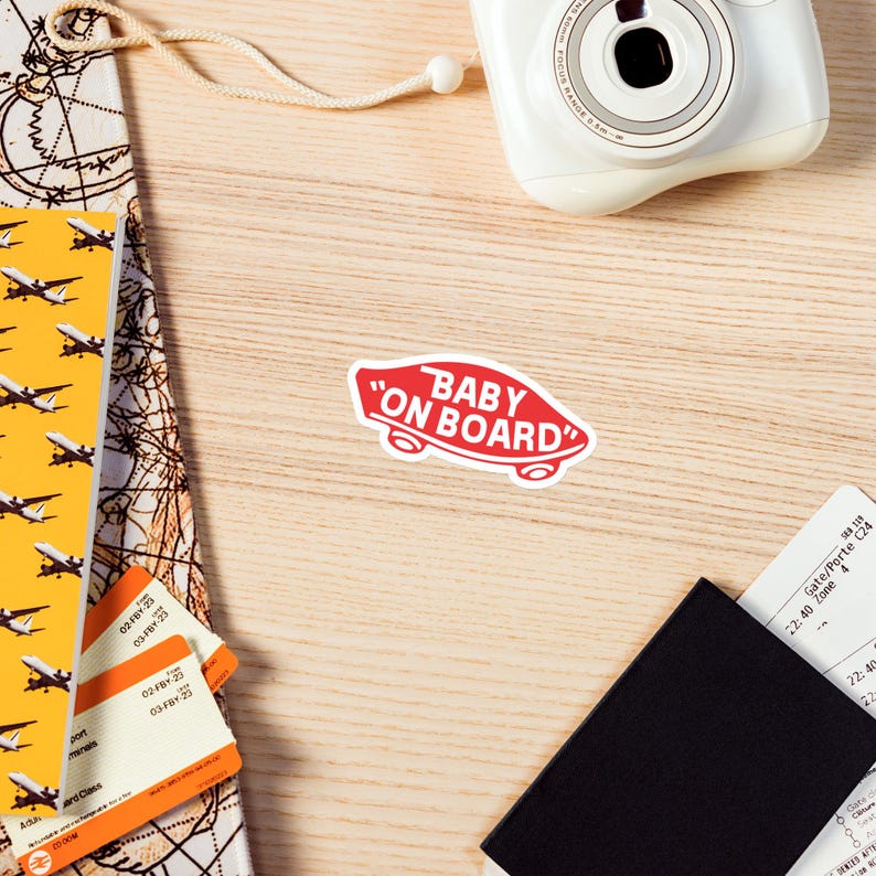 Peut inclure: Autocollant rouge et blanc avec le texte "Baby on Board" en contour blanc. L'autocollant a la forme d'une planche &agrave; roulettes.