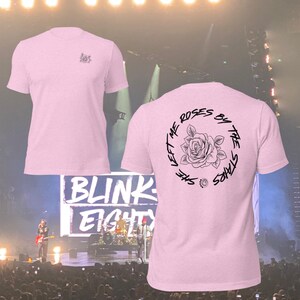 May include: Pink t-shirt with a black graphic on the back that says "She left me roses by the stars" with a rose illustration. The front of the shirt has a small graphic of a rose.