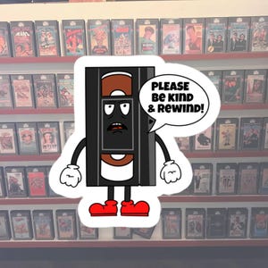 May include: A cartoon illustration of a VHS tape with legs and arms. The tape is wearing a red hat and has a speech bubble that says "Please be kind & rewind!"