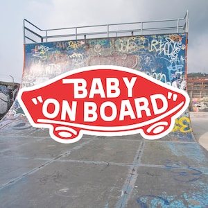 Peut inclure: Un autocollant rouge et blanc avec le texte "BABY "ON BOARD" sur une rampe en b&eacute;ton recouverte de graffitis.