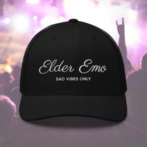 May include: Black trucker hat with white embroidered text that reads "Elder Emo Sad Vibes Only".