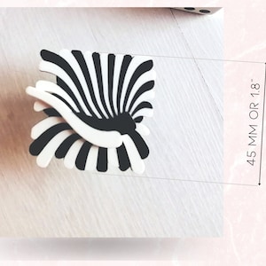Peut inclure: Objet d&eacute;coratif &agrave; rayures noires et blanches en forme d'&eacute;ventail. L'objet mesure environ 4,5 cm de haut.