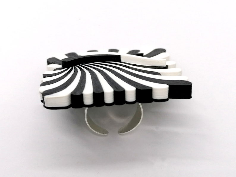 Peut inclure: Une bague &agrave; rayures noires et blanches avec une bande argent&eacute;e. La bague est en forme de soleil.