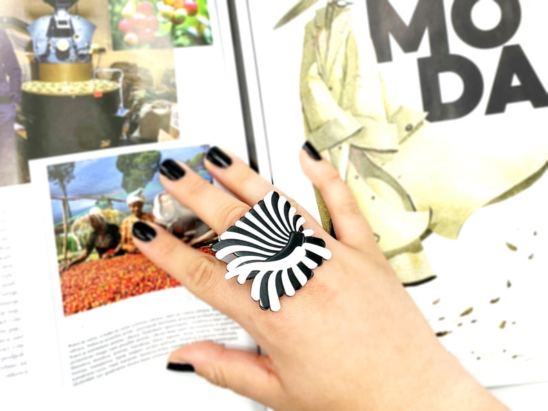 Peut inclure: Une bague noire et blanche avec un motif g&eacute;om&eacute;trique. La bague est en plastique et a une finition brillante.