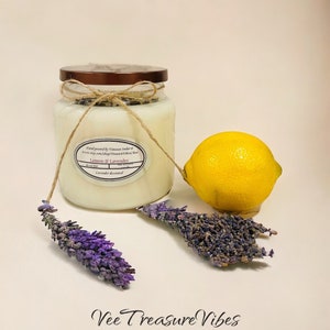 May include: A glass jar candle with a brown lid and a white label that reads "Hand poured by Vanessa Indar", "Lemon & Lavender", and "Lavender decorated". The candle is next to a lemon and dried lavender sprigs.