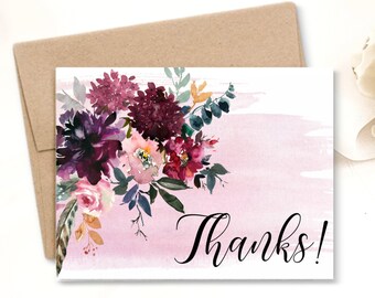 May include: A thank you card with a watercolor floral design in shades of pink, burgundy, and green. The card has a pink watercolor background with a white border and the word "Thanks!" in black cursive.