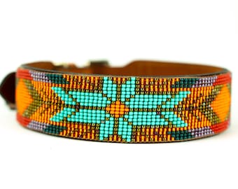 May include: A brown leather dog collar with a colorful beaded design. The design features a turquoise flower with orange and yellow accents.