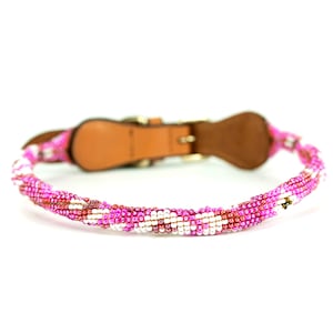 Puede incluir: Un collar de perro de cuentas rosa, blanco y marrón con una base de cuero marrón y una hebilla plateada.