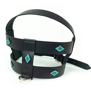 May include: Black leather dog harness with turquoise beaded accents. The harness has a chest strap, a back strap, and a ring for attaching a leash.