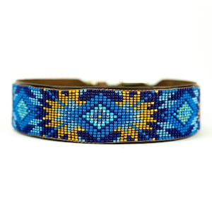 May include: A wide leather collar featuring a geometric pattern created with small glass beads in shades of royal blue, light blue, and golden yellow. The beadwork displays repeating diamond and star motifs across the entire outer surface.