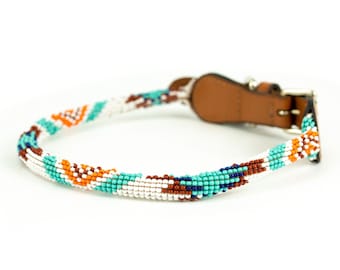 May include: A beaded dog collar with a brown leather buckle. The beads are white, turquoise, orange, and brown.