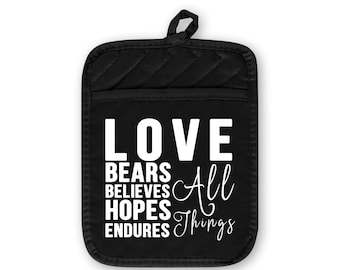 May include: Black oven mitt with the words "LOVE BEARS BELIEVES HOPES ENDURES All Things" in white lettering. The mitt has a quilted pattern and a loop for hanging.