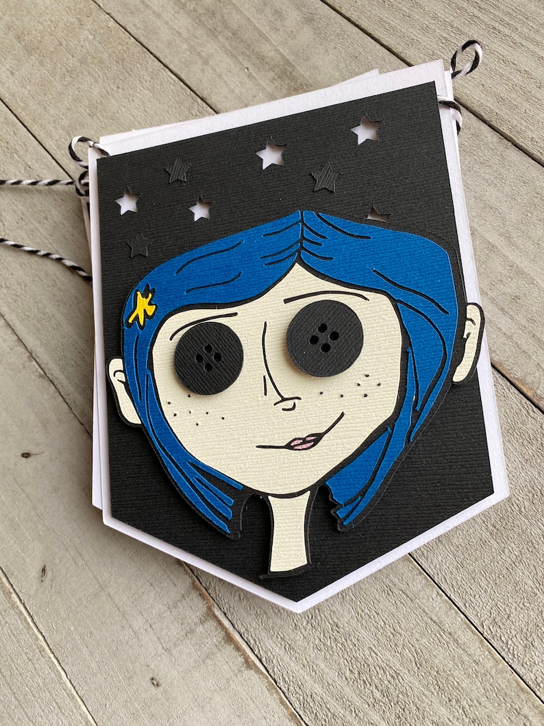 May include: A black and white banner with a cutout of a girl's face. The girl has blue hair, large black eyes, and a small yellow star on her cheek. The banner has a white border and is decorated with white stars.