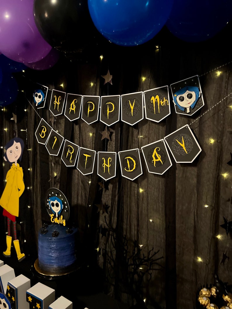 May include: A black and gold birthday banner with the words "Happy 11th Birthday" and a character from the movie "Coraline" on each end. A blue cake with a topper of the same character is in the foreground.