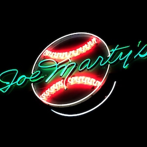 May include: Neon sign with a baseball graphic and the text "Joe Marty's" in green.
