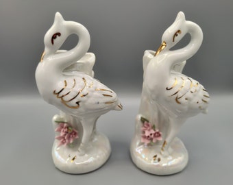 Puede incluir: Par de figuras de cisnes de cerámica blanca con detalles dorados y flores rosas. Los cisnes tienen un acabado nacarado y están sobre una base. Decoración del hogar.