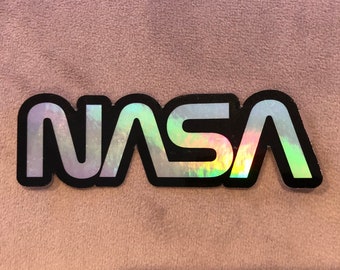 May include: A silver iridescent sticker with the word "NASA" in black lettering.