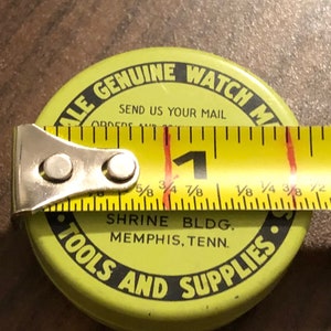 May include: A yellow metal container with black text that reads "ALE GENUINE WATCH M" and "TOOLS AND SUPPLIES". The container also has the text "SEND US YOUR MAIL" and "SHRINE BLDG. MEMPHIS, TENN."