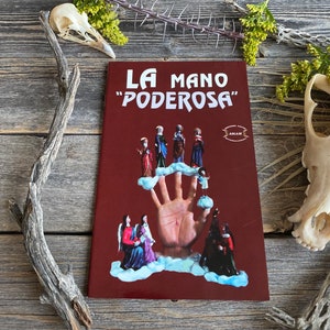 May include: A red book with the title "La Mano "Poderosa" written in white. The cover features an illustration of a large hand with several figures standing on its fingers. The figures are dressed in colourful robes and appear to be religious.