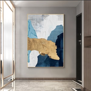 Peut inclure: Impression d'art abstrait avec des coups de peinture bleus, blancs et dorés. L'impression est encadrée dans un cadre doré.