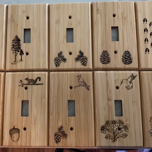 May include: Set of 12 light brown wooden light switch covers with various nature-themed designs, including animals, birds, plants, and footprints.