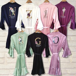 May include: Six satin robes in different colors with floral designs and a gold letter on the back. The robes have ruffled sleeves and a ruffled hem. The letters on the robes are N, Z, J, I, R, and G.