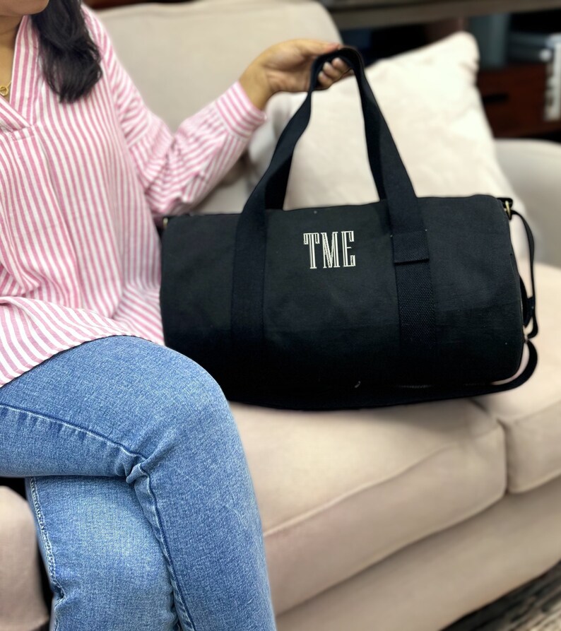 May include: A black canvas duffel bag with a white embroidered monogram "TME".