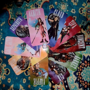 May include: A collection of Final Fantasy VII character cards, each featuring a different character illustration and name. The cards are arranged in a circular pattern on a patterned surface. Characters include Aerith, Cloud, Tifa, and others.