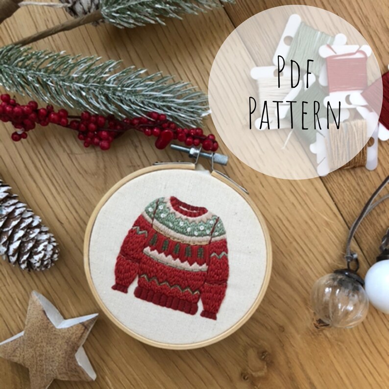 Puede incluir: Patr&oacute;n de su&eacute;ter de Navidad bordado en un aro. El su&eacute;ter es rojo con detalles en verde, blanco y marr&oacute;n. El patr&oacute;n est&aacute; disponible para descargar en PDF.