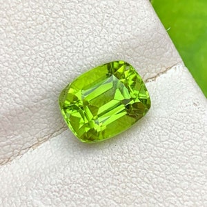 May include: A vibrant green gemstone with a cushion cut, displayed on a white background.