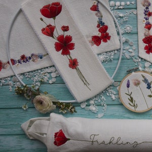 May include: Three white fabric panels with embroidered red poppies and green stems. The panels are decorated with lace and the word "Frühling" is embroidered on one panel.