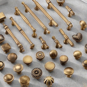 Könnte beinhalten: Eine Sammlung von antiken Messing-Schrankbeschlägen, darunter Knöpfe und Griffe. Die Knöpfe sind rund, quadratisch und blumenförmig. Die Griffe sind stangenförmig mit dekorativen Details.