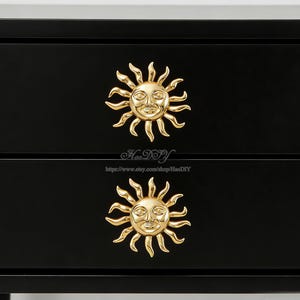 May include: A black chest of drawers featuring two gold-coloured sun-shaped handles. Each handle has a smiling face at its centre and radiating rays. The text "HaoDIY" and a website address are visible.