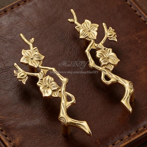 May include: A set of three ceramic mugs with a speckled, matte finish. The mugs are in shades of cream, light gray, and dark gray. Each mug has a simple, minimalist design and a rounded handle.