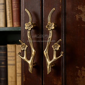May include: Antique brass cabinet pulls with a floral branch design. The pulls are mounted on a dark wood cabinet door. The image includes the text "HaoDIY" and a website address.