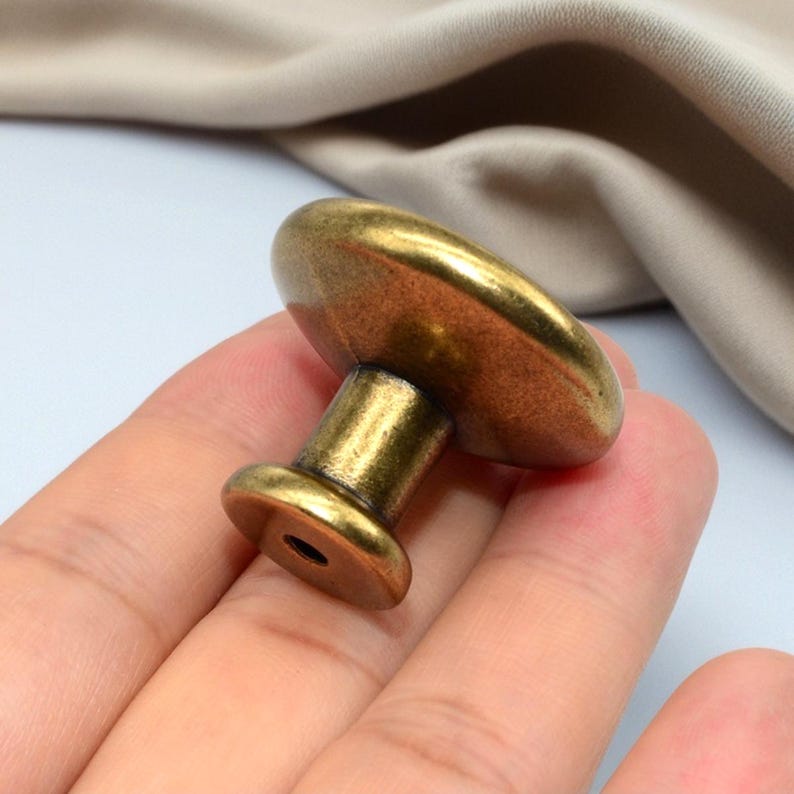 Puede incluir: Pomo de armario de lat&oacute;n antiguo con una parte superior redondeada y una base cil&iacute;ndrica. El pomo tiene una est&eacute;tica vintage, adecuado para la restauraci&oacute;n de muebles o para a&ntilde;adir un toque cl&aacute;sico a armarios y cajones.