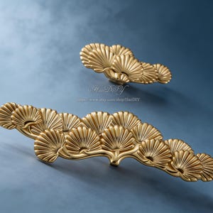 Könnte beinhalten: Eine weiße Keramik-Tasse mit schwarzem Henkel und dem Text "But First, Coffee" in schwarzer, fetter Schrift. Die Tasse steht auf einer weißen Oberfläche.