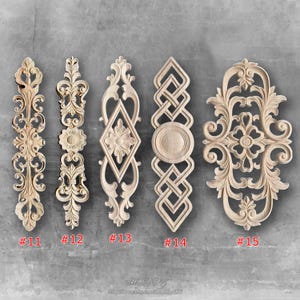 May include: Five unfinished wooden decorative carvings with intricate floral and geometric designs. Each piece is a different shape and size, with numbers #11, #12, #13, #14, and #15 visible. The carvings are displayed against a gray background.